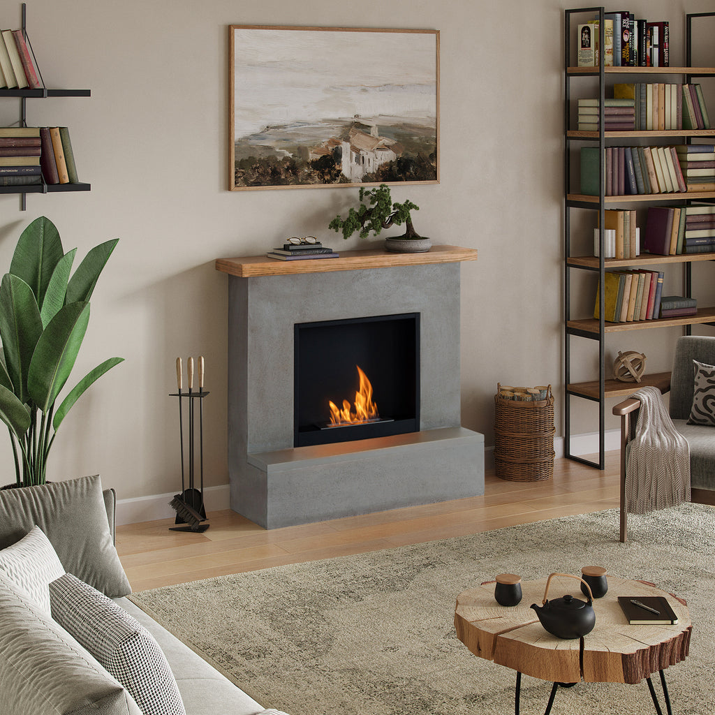 Living room with a concrete fireplace, bookshelf, and decorative items.